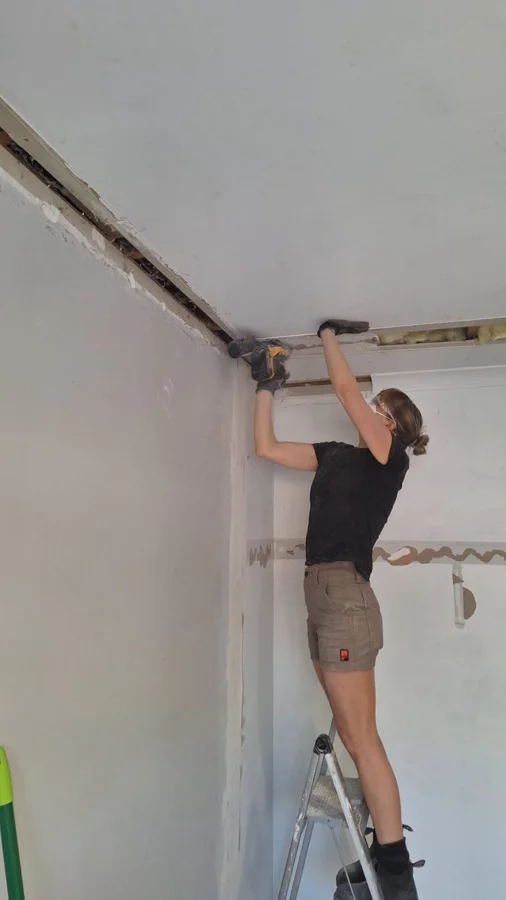 Meg up a ladder sanding in the dressing room