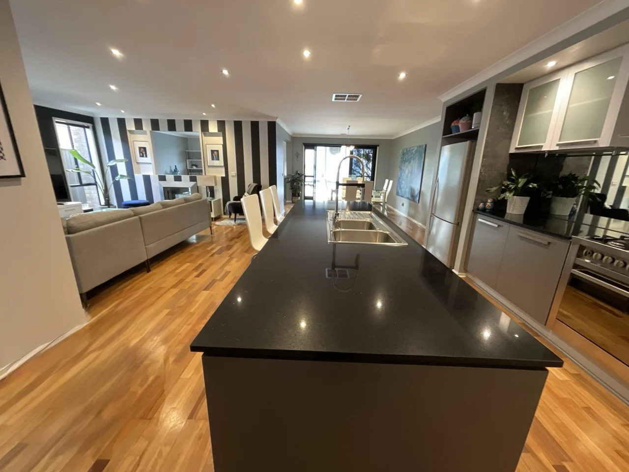 Before: the same room with a black island bench, white bar stools and a striped feature wall