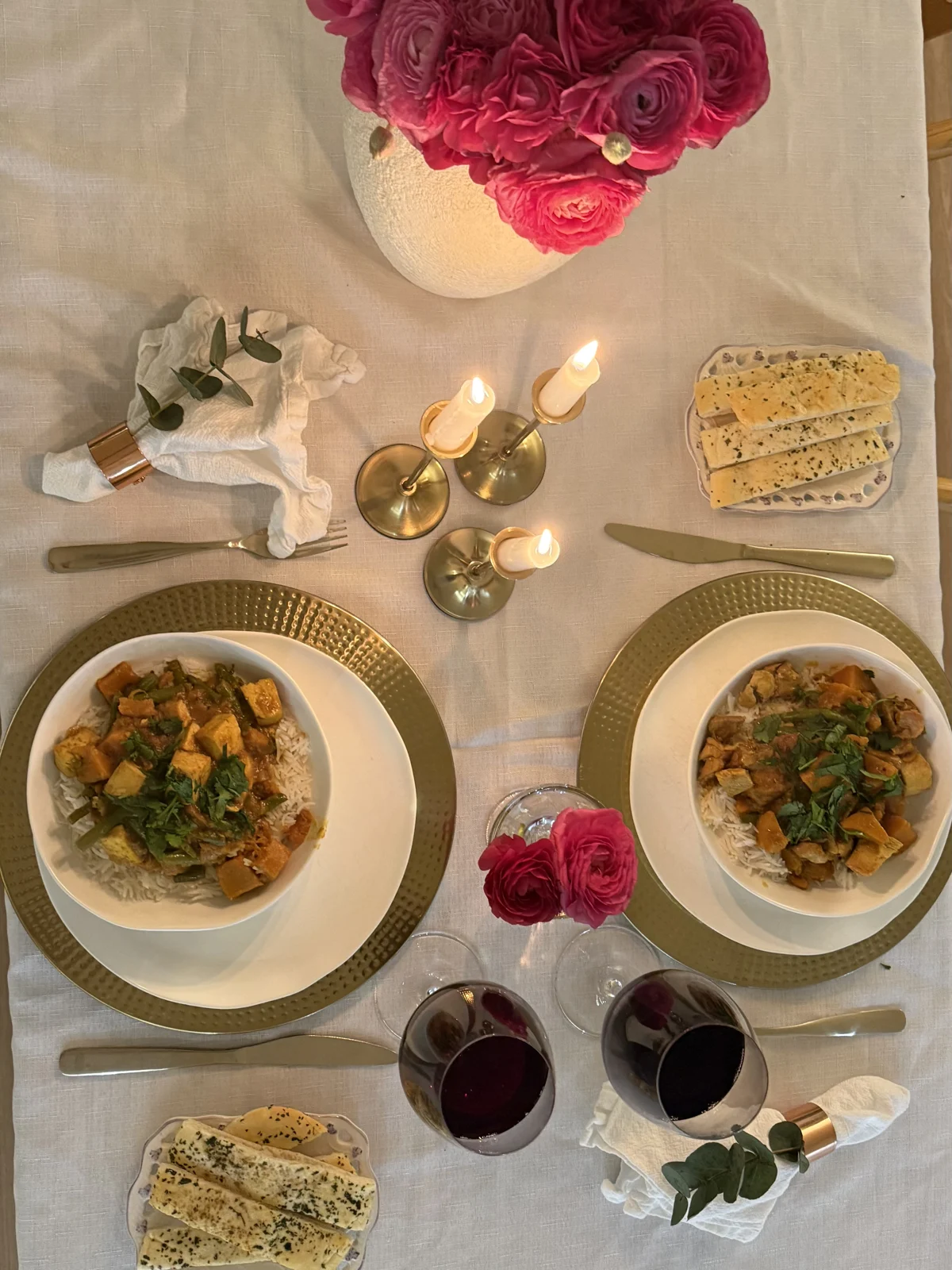 The same table served: curry on rice, garlic bread, red wine and the candles lit